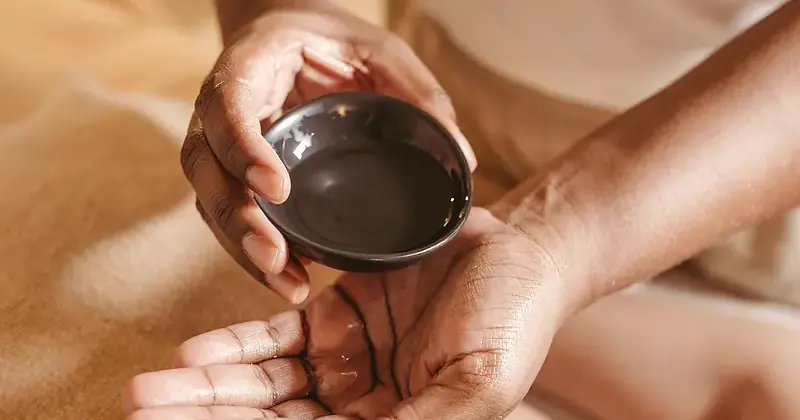 Therapist pouring warm massage oil during a ritual at BodyBar Studio